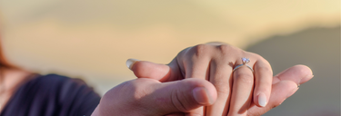 A couple holds hands happily, the woman wears a lab-grown diamond engagement ring on her hand