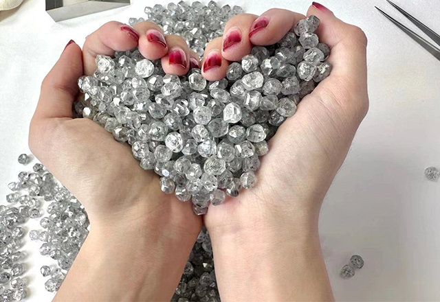 Hand holding a pile of lab-grown rough diamonds